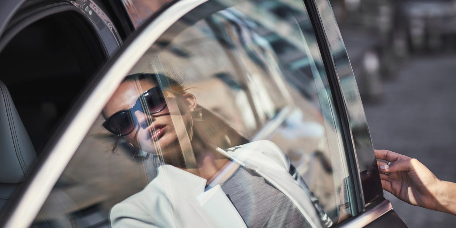 A womans reflection on the window of an INFINITI car